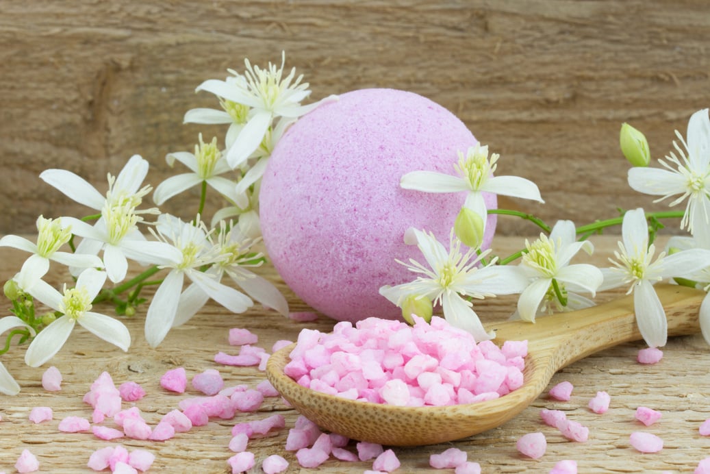 pink bath bomb and salt in wooden spoon